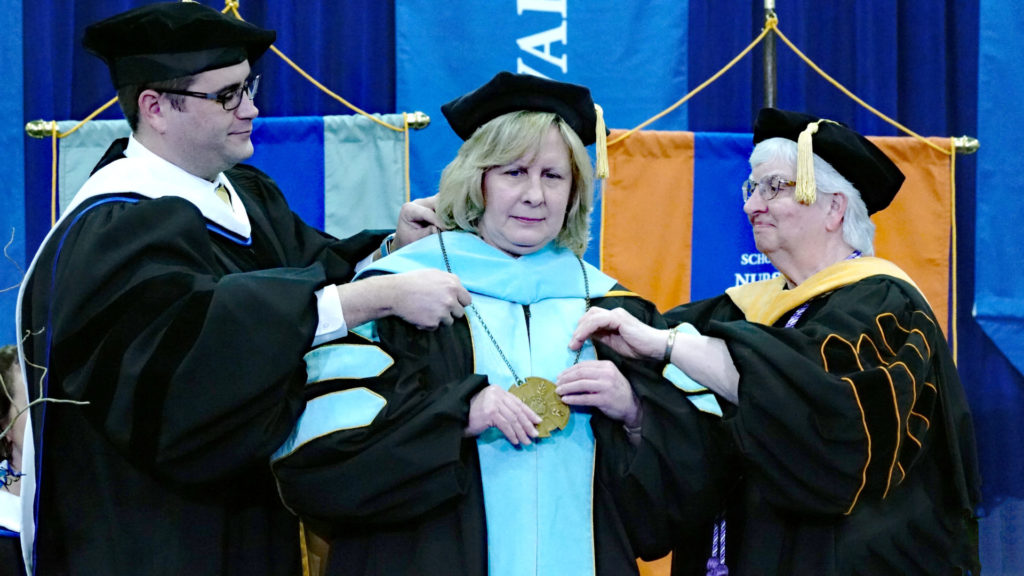 Christopher Dolan and Sr Beverly Raway place medallion on the new president.