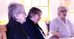 Sisters Melanie Gagne, Goria Ess, and Josine Krausnick celebrate with the other Sisters on Benet Hall.